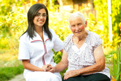 A young doctor / nurse visiting an elderly sick women holding her hands