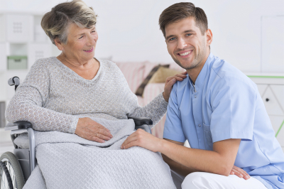 Positive senior women on a wheelchair and smiling male carer